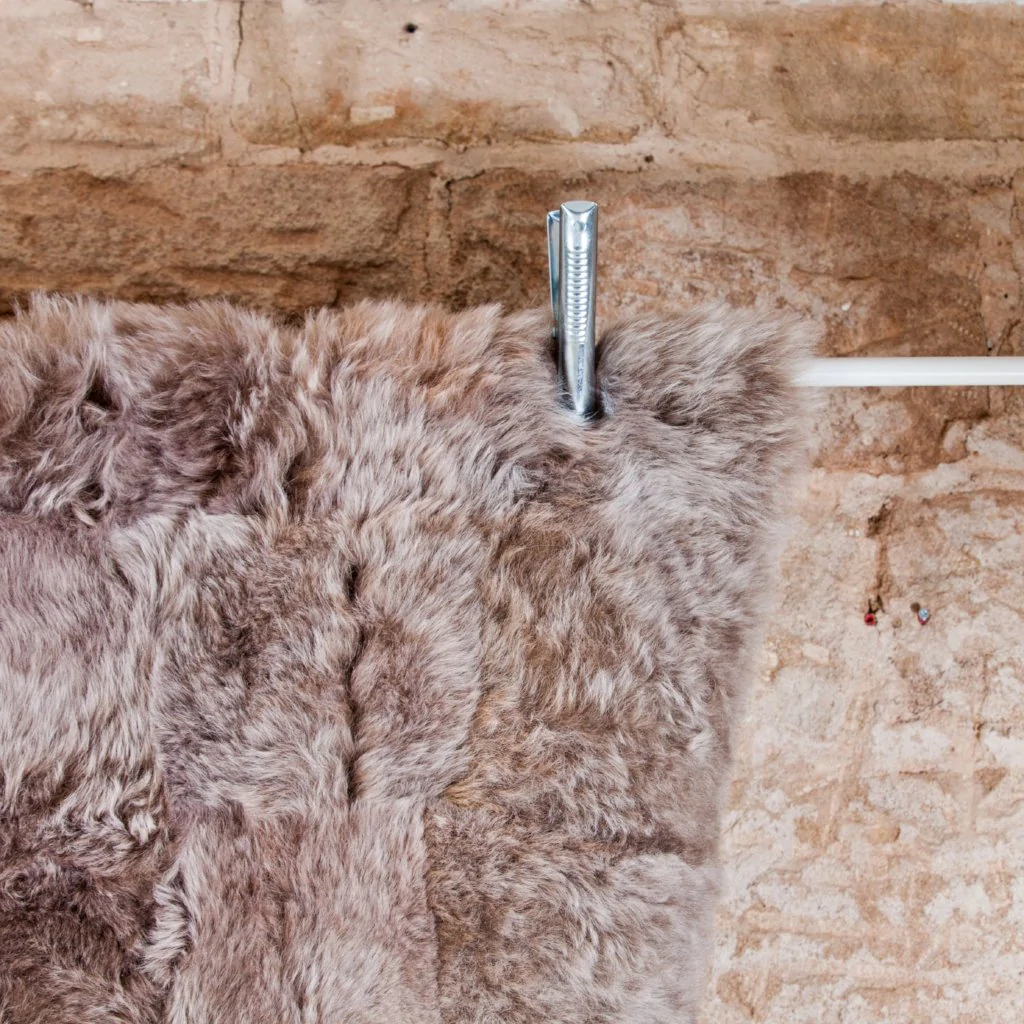 Taupe Icelandic Designer Sheepskin rug, draped over a pole.