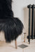 Detail of s deep black/brown Icelandic Sheepskin Long Wool Rug. Draped over a brown wooden chair.