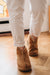 Lady in white trousers wearing Sheepskin slipper Boots with a sole walking on a wooden floor