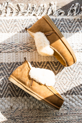 Albina Sheepskin Slipper with cuff in Camel, made by Shepherd of Sweden. Photographed on grey patterned rug.