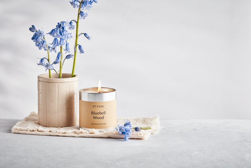 St. Eval Bluebell Wood Tin Scented Candle. Featured next to a cermaic pot with bluebells.