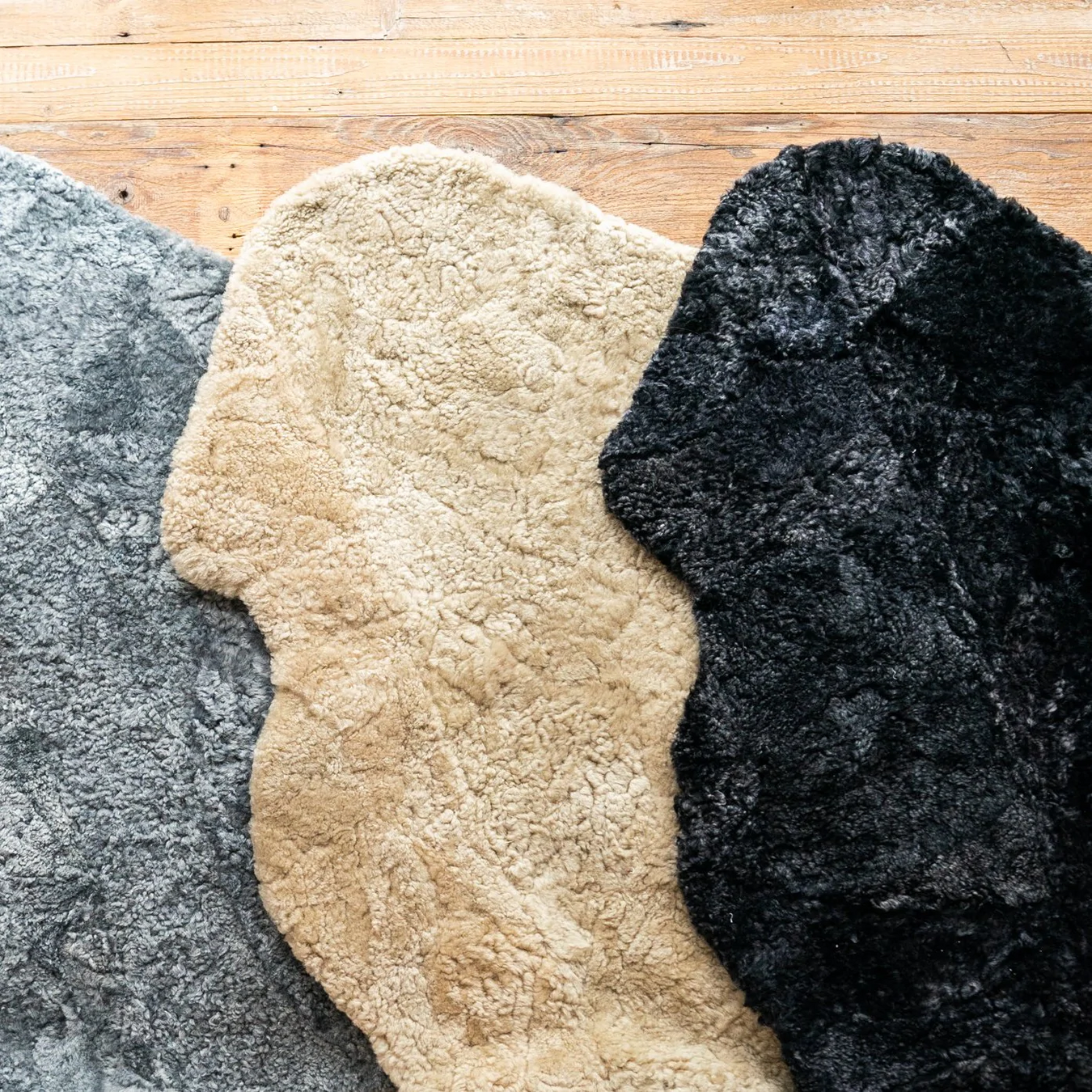 Wasteless sheepskin rugs, features three rugs in Meringo Grey, Oatmeal and Black Smoke staked on top of one another.