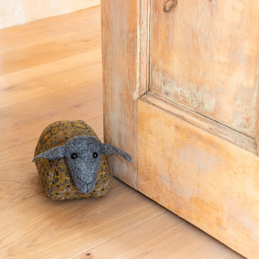 Woven wool sheep shaped doorstop, with dark grey face and mustard yellow and grey patterned body