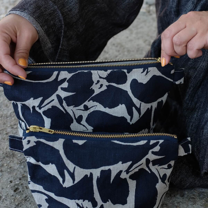 Model unzipping top of large Small Creatures Abstract Pattern Navy Blue Wash Bag from Blästa Henriët. Comes in small and large, Linen Wash bag.