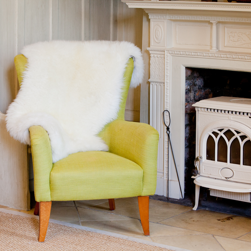 A British White / Cream Natural dense wool rug, dressed on a yellow chair in a living room.
