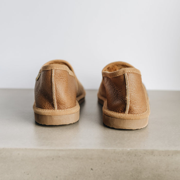 Rear heel of Donald Sheepskin Men's Slippers. Features a warm brown leather with complimentary beige seams and sole.