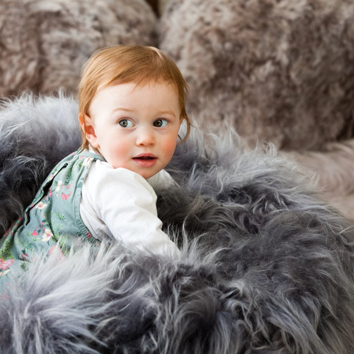 A child sits ontop of a grey long wool Icelandic Sheepskin Bean Bag. 