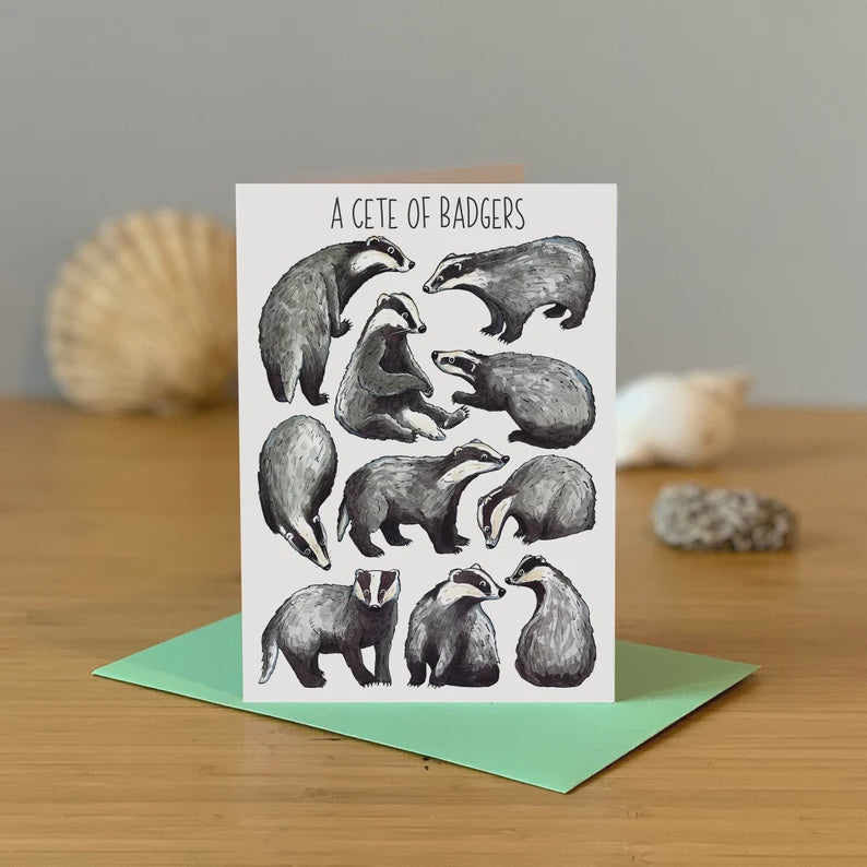'A Cete Of Badgers' Designed Greetings Card. A white background with 10 grey, white and black badgers stood and sat. At the top is the writing 'A Cete Of Badgers' Comes with a colourful envelope.