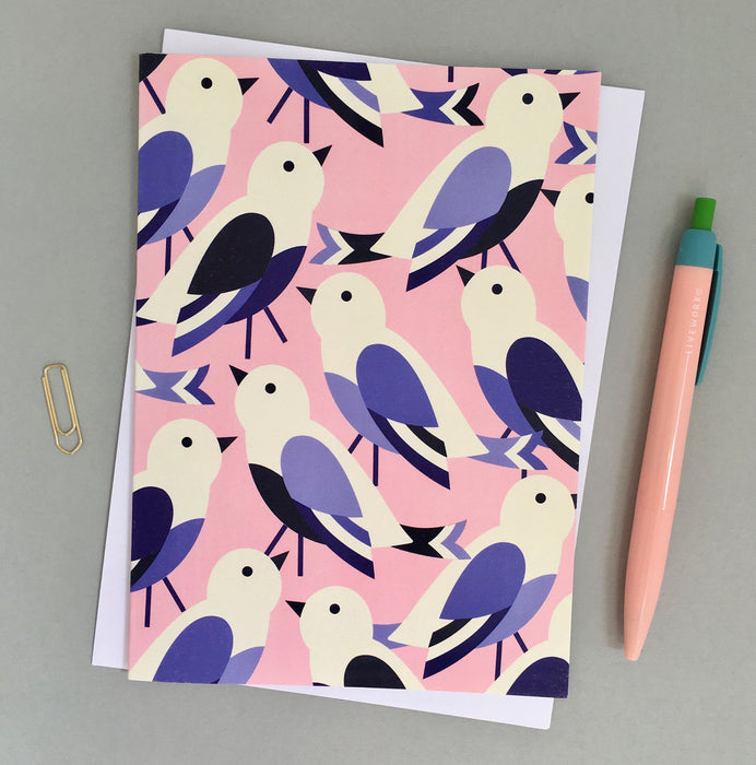 Chricks Designed Greetings Card. A vertical rectangular card, with a pink background. Features minimalistic white birds with blue features, looking in different directions. Comes with an envelope.