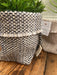 A close up of the Ragmakers woven wool texture on the Charcoal Grey, White and Cream basket. Inside is a plant. To its right is a Cream and White Milnsbridge Basket.