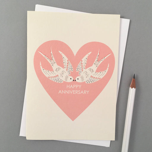 Happy Anniversary Card. A white verticle card, features a pink loveheart shape with two white doves. In the centre reads 'Happy Anniversary'. Comes with an envelope.